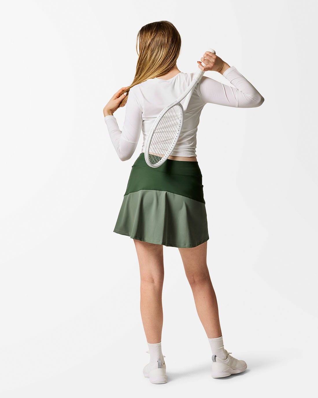 Sportkjol sedd bakifrån. Tvåfärgad. Mörkgrön överst och dimgrön nederst. Klockad bak.