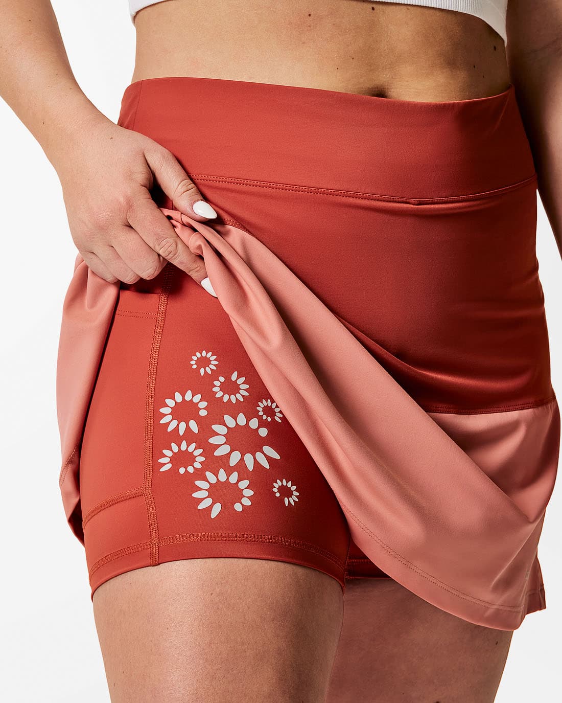 Sportkjol med blomtryck på innerbyxan. Tvåfärgad. Korallröd överst och aprikos nederst.